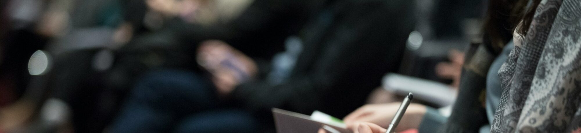 selective focus photography of people sitting on chairs while writing on notebooks